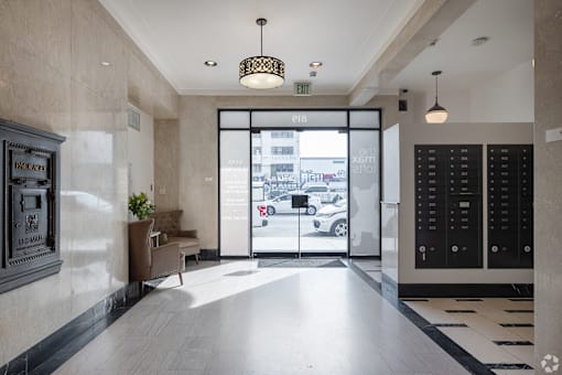 A hallway with a black and white checkered floor, a black door, and a white wall with a framed picture on it.