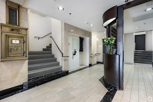 A hallway with a staircase and a black marble floor.