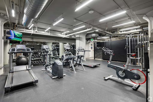 A gym with a variety of equipment including treadmills, weights, and exercise machines.