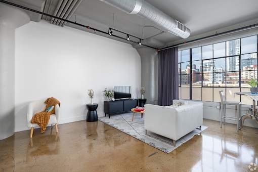 A living room with a white couch and a chair with a yellow blanket on it.