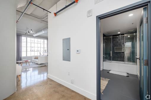 A room with a white wall and a door leading to another room.
