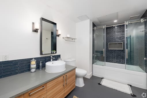 Updated bathroom with oversized vanity, modern fixtures, and beautiful blue tile backsplash on the vanity and along the wall of the shower/tub
