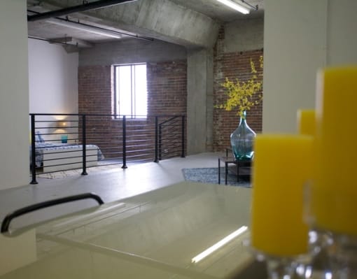 a room with a bath tub and a vase with yellow flowers at Binford Lofts Apartments, Los Angeles 