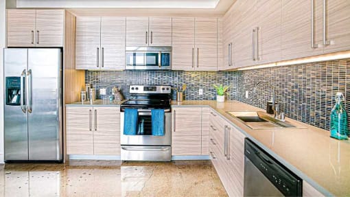 a kitchen with stainless steel appliances and white cabinets at Maxfield Lofts, Los Angeles, CA 90014 