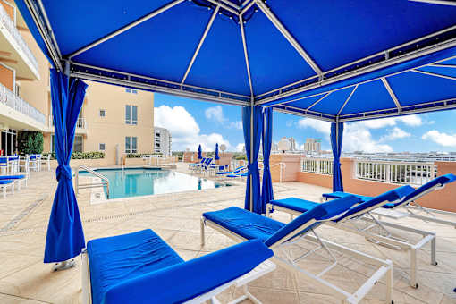 A blue umbrella shaded a sun lounger on a patio.