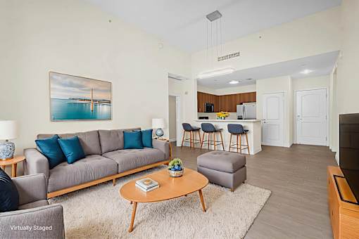 A living room with a grey couch and a painting of a bridge over water.