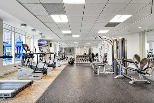 A gym with a variety of equipment including treadmills, weights, and exercise machines.