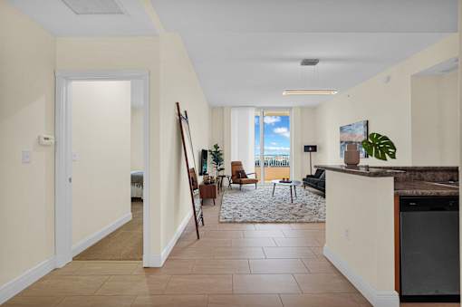 A hallway with a tiled floor and a large window with a view of the sky.