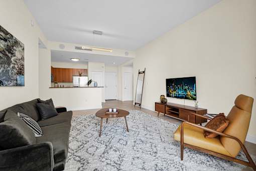 A living room with a black couch, a brown chair, and a TV.