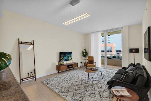 A living room with a grey rug and a black couch.
