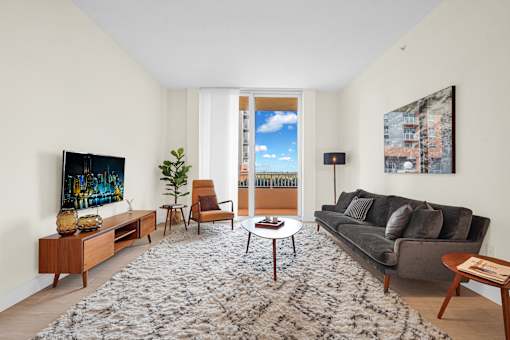A living room with a grey couch, a wooden coffee table, a TV, and a painting on the wall.