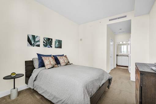 A bedroom with a bed, a nightstand, and a painting on the wall.