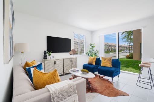 a living room with white tile flooring and a sliding glass door that leads to a yard