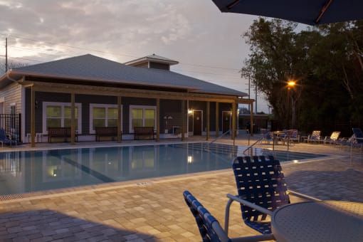 A poolside area with a house and chairs.