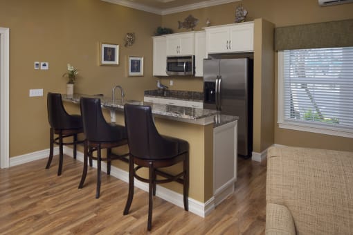 A kitchen with brown chairs and a white fridge.