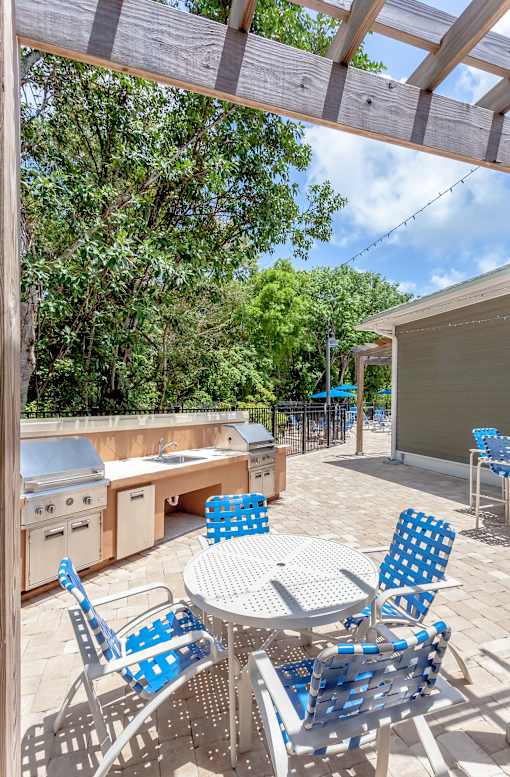 A patio with a table and chairs under a wooden pergola.