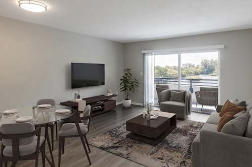 A modern living room with a glass table and grey chairs.