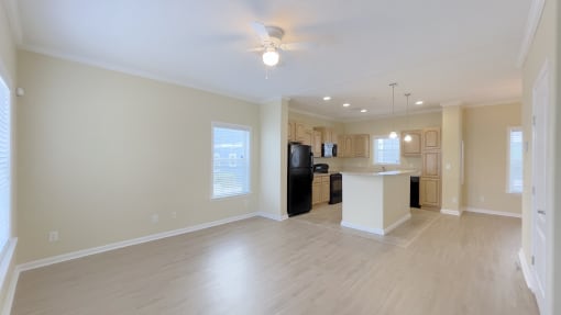 A spacious living room with a kitchenette in the background.