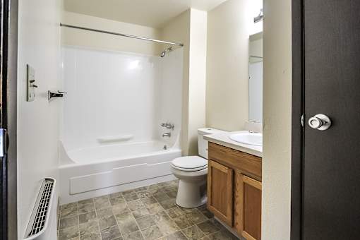 A bathroom with a white tub, toilet, and sink.