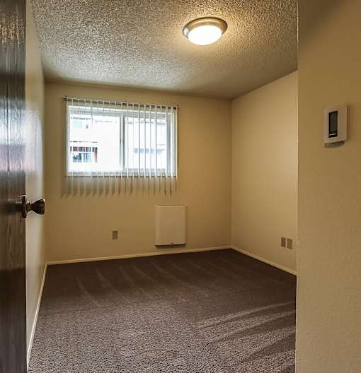 A room with a window covered by white blinds and a white radiator on the wall.