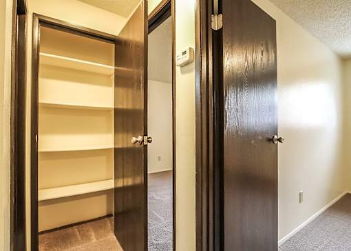 A hallway with a black door on the right and a white door on the left.
