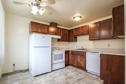 A kitchen with white appliances and brown cabinets.