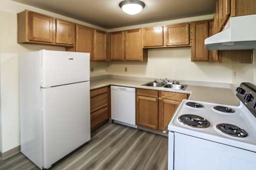 A white refrigerator is in a kitchen with wooden cabinets.