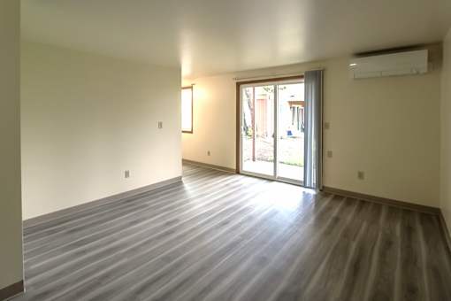 A room with a wooden floor and sliding glass doors.