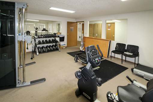 A gym with a variety of equipment including weights, treadmills, and exercise machines.