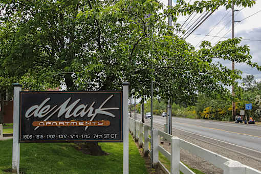 A sign for deMark Apartments is displayed by the roadside.