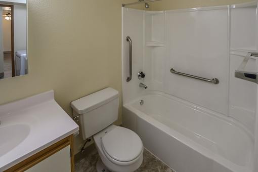 A white toilet sits next to a white bathtub in a bathroom.