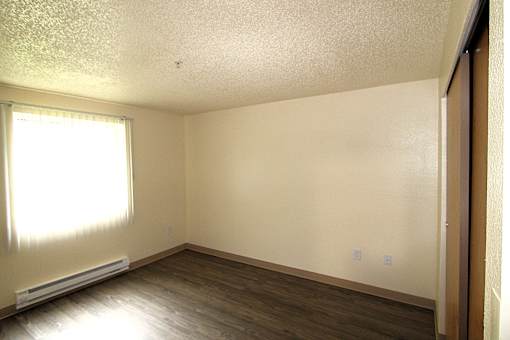 A bedroom with a window and a wall-mounted air conditioner.