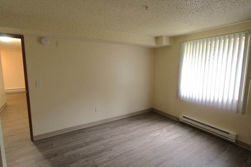 A bedroom with a window and an electric heater on the wall.