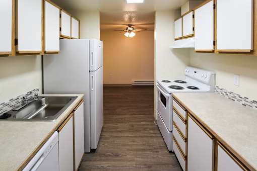 A kitchen with white appliances and wooden cabinets.