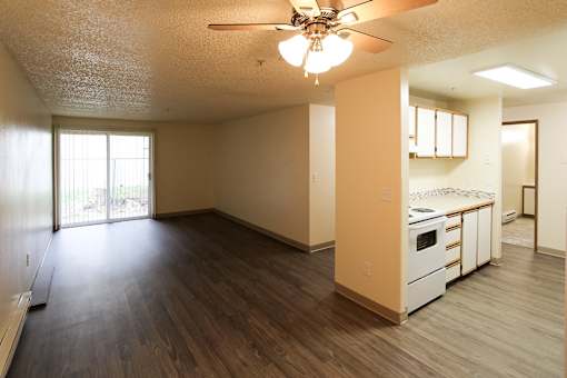 The living room with a ceiling fan and wooden flooring.
