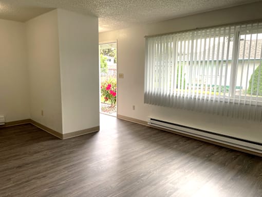 A room with wooden floors and a window with blinds.