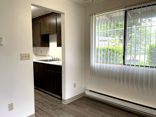 A kitchen with white walls and wooden cabinets.