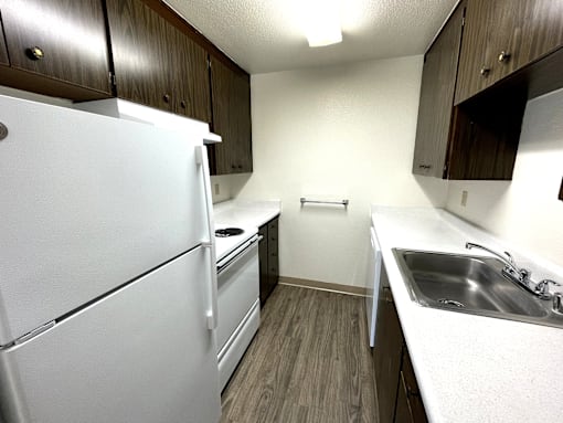 A white refrigerator is in a kitchen with wood cabinets.