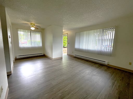 A room with a ceiling fan and two windows with blinds.