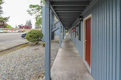 A long grey building with a red door.