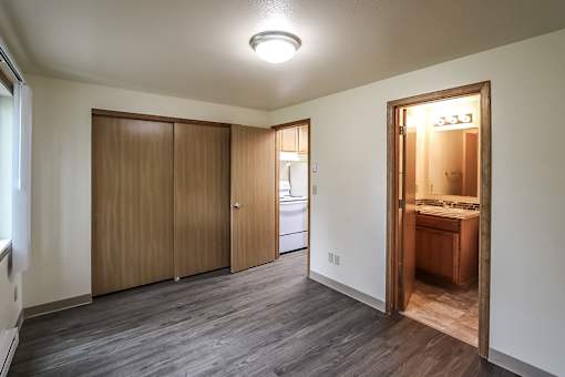 A room with a kitchen area in the back and a doorway leading to another room.