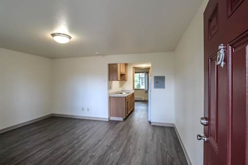 A room with a red door and a kitchen area in the background.