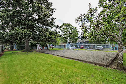 A playground with a swing set and a slide in the background.