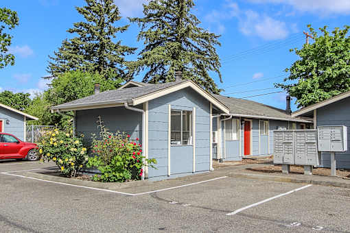 A small blue house with a red car parked in front.