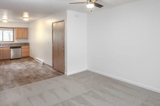 a living room with a ceiling fan and a kitchen in the background