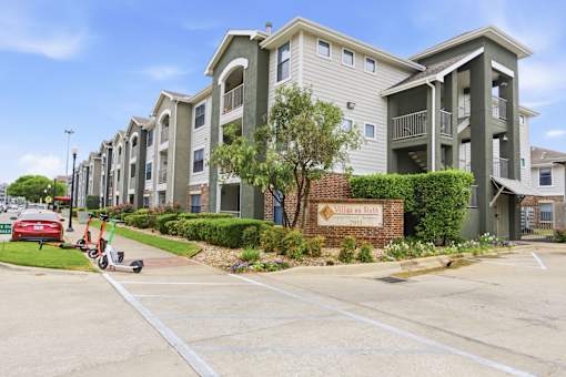 A row of apartment buildings with a sign that says "Villages at Hillcrest".