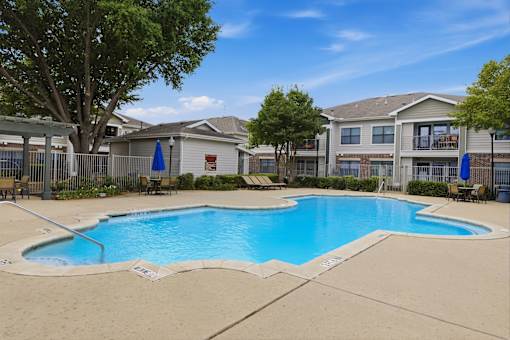 A swimming pool in a residential area surrounded by houses and trees.