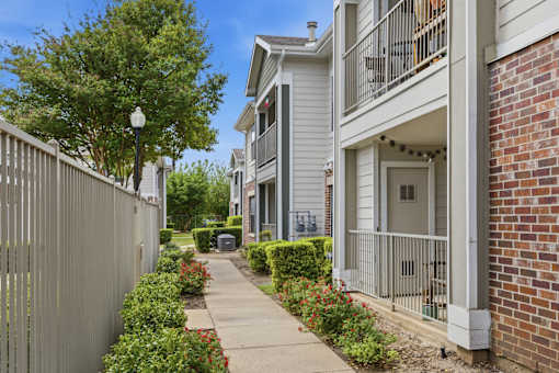 A residential street with a sidewalk and a metal fence.