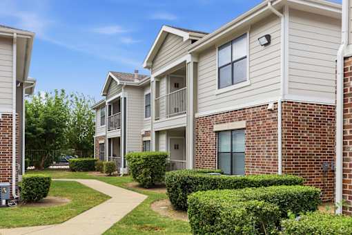 A row of houses with a sidewalk in front.
