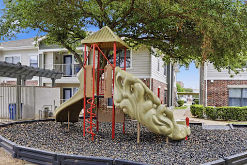A playground with a slide and a tree in the background.